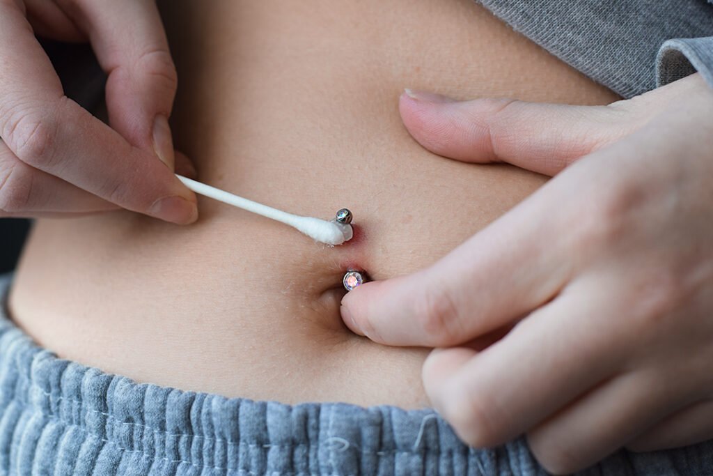 Limpiando piercing en el ombligo con un isopo